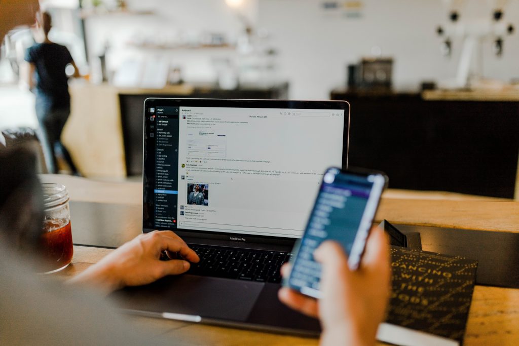 A person holding the phone and working on his laptop